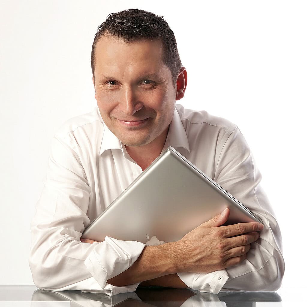 portrait professionnel en studio réalisé à lyon. homme en chemise blanche avec ordinateur portable, photo corporate par photographe portrait professionnel lyon.