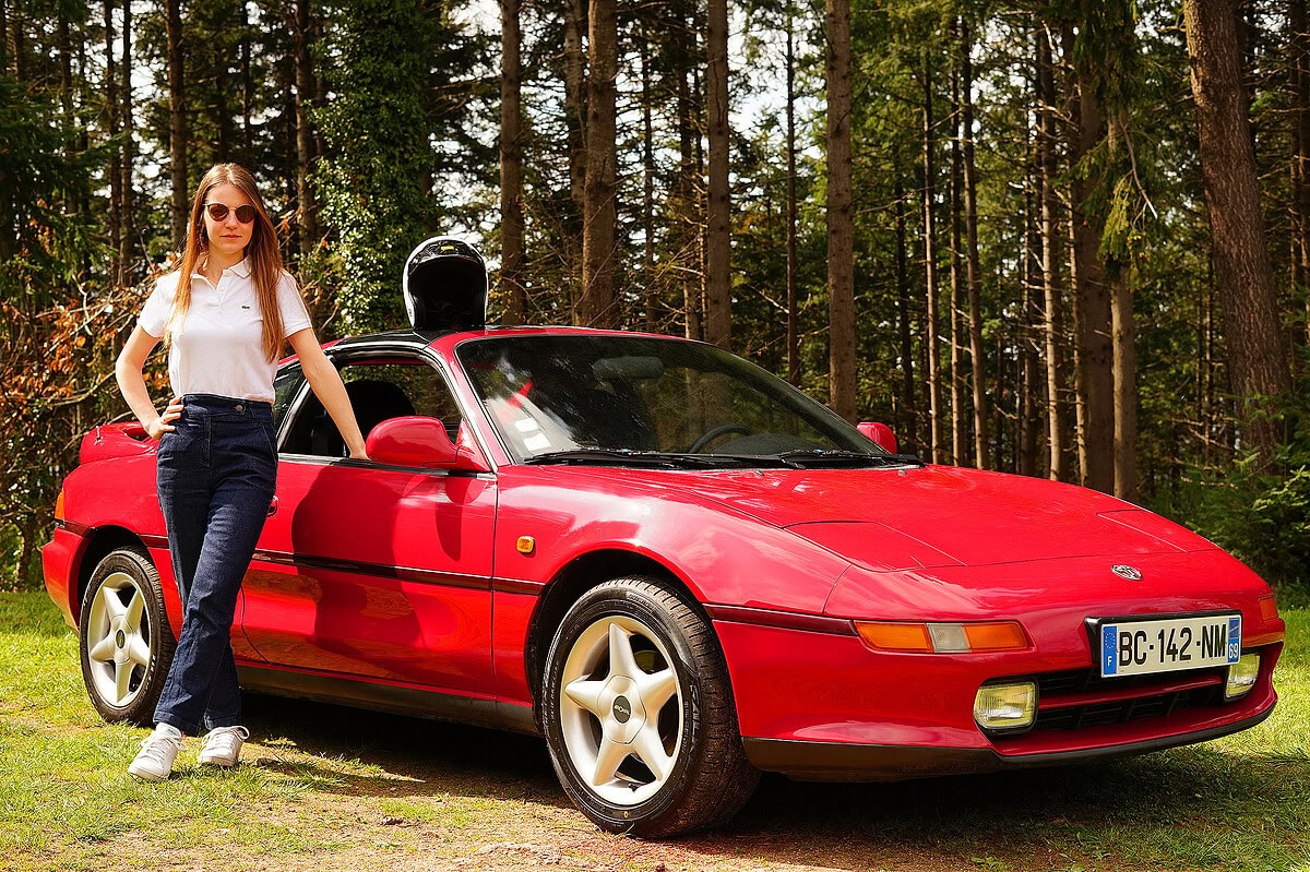 portrait professionnel réalisé à lyon. jeune femme posant avec sa voiture rouge, photographie lifestyle par un photographe portrait professionnel lyon.
